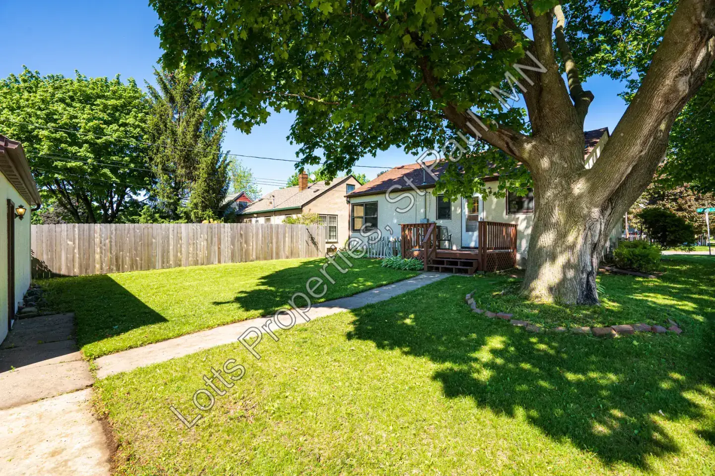 Shaded backyard seating and lawn beneath mature trees