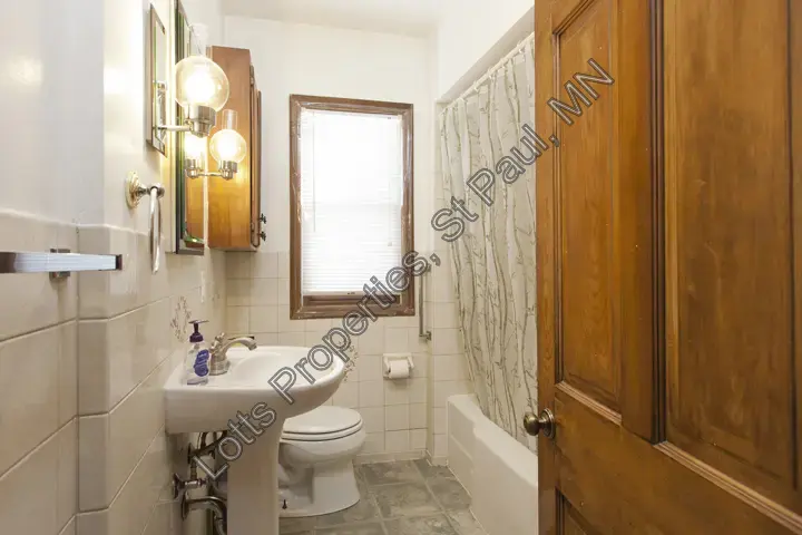 Full bathroom with pedestal sink, storage cabinet, and shower
