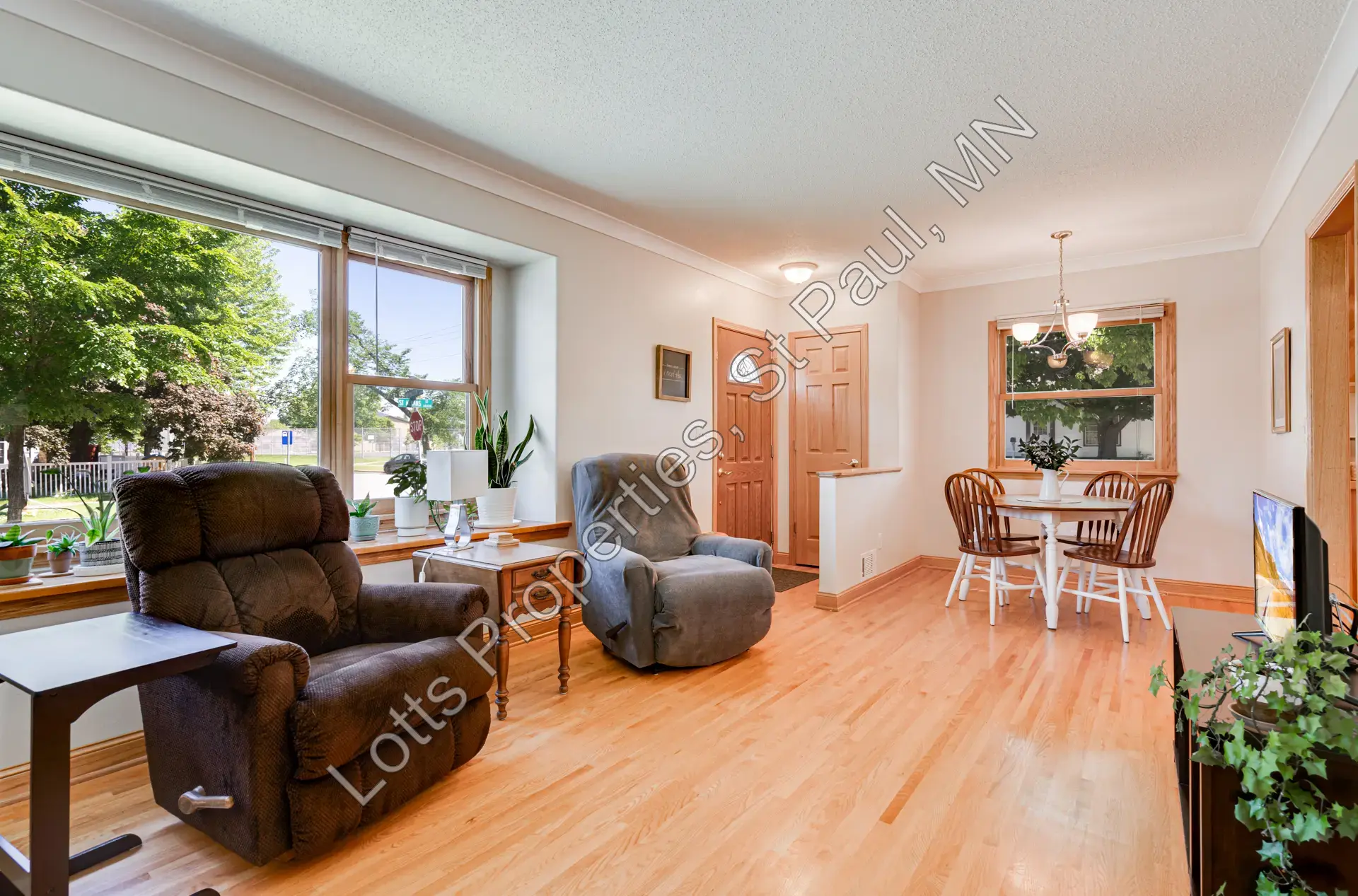 Living room with hardwood floors, large front windows, and a built-in window seat