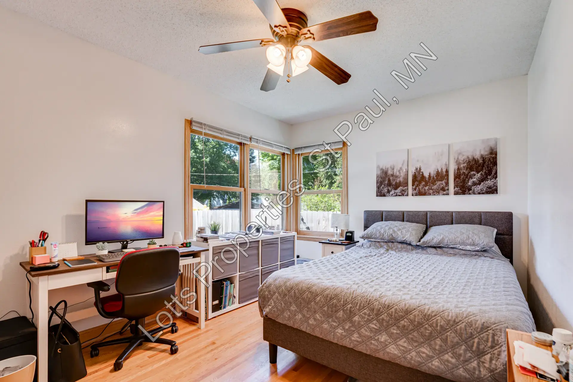 West main-floor bedroom at the back of the house with hardwood floors and ceiling fan