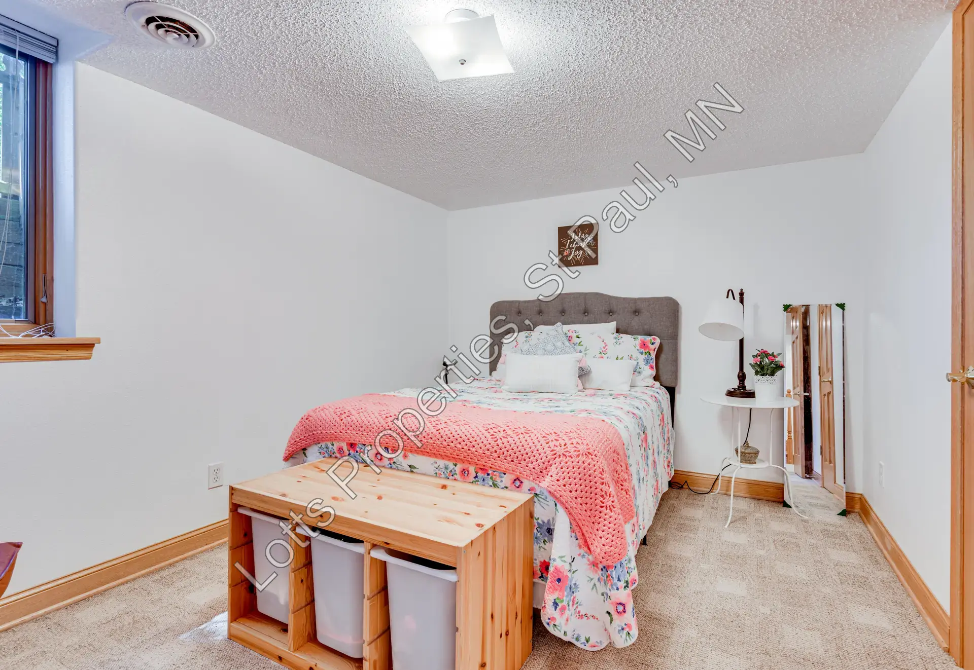 Lower-level west bedroom with bed, egress window, and wood-look flooring