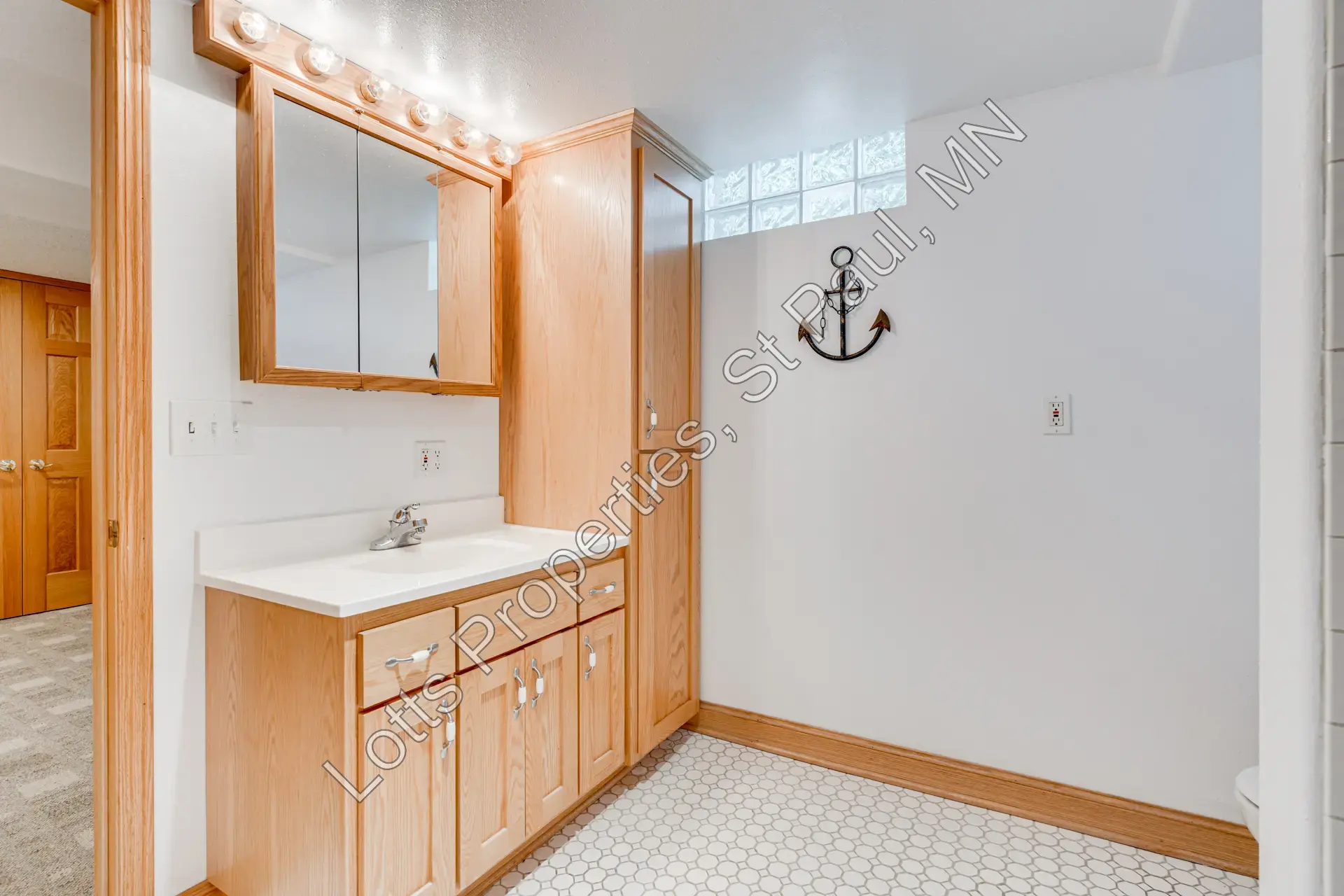 Lower-level bathroom vanity with built-in storage and mirror lighting