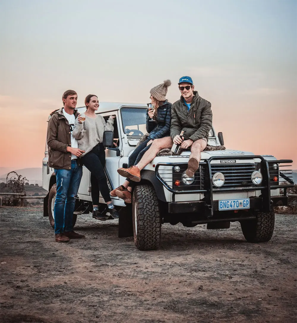 Group of four people around a jeep in the countryside