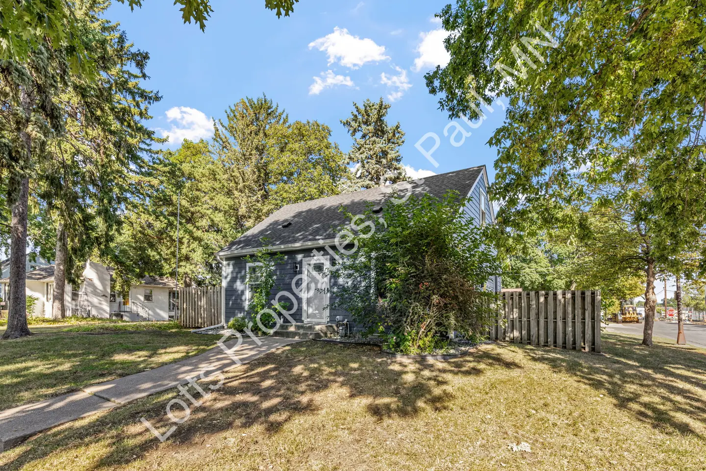 Exterior side view of 1444 Alameda surrounded by trees with a walkway and privacy fence.