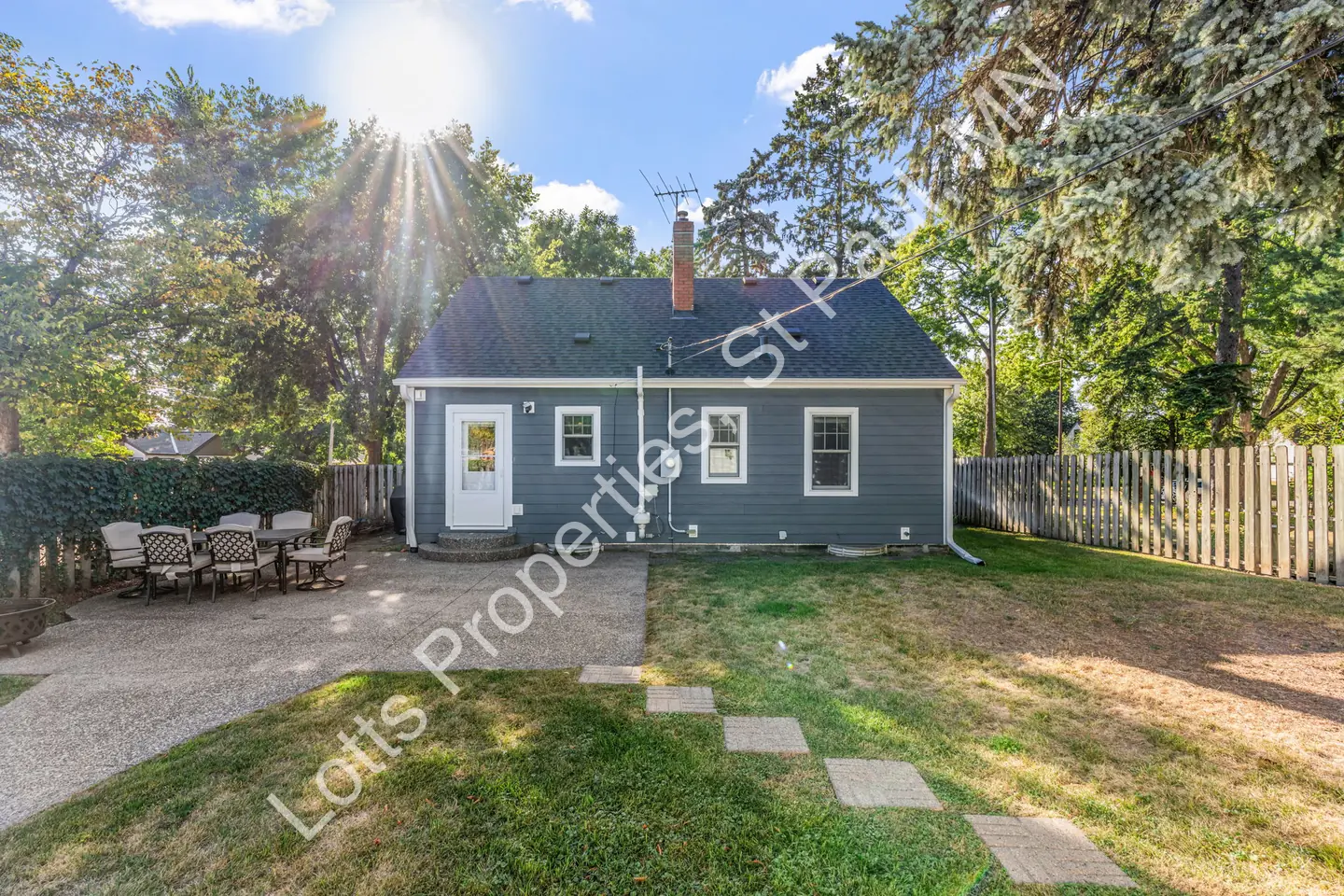 Backyard of 1444 Alameda with a patio, stepping stones, and privacy fencing under bright sun.