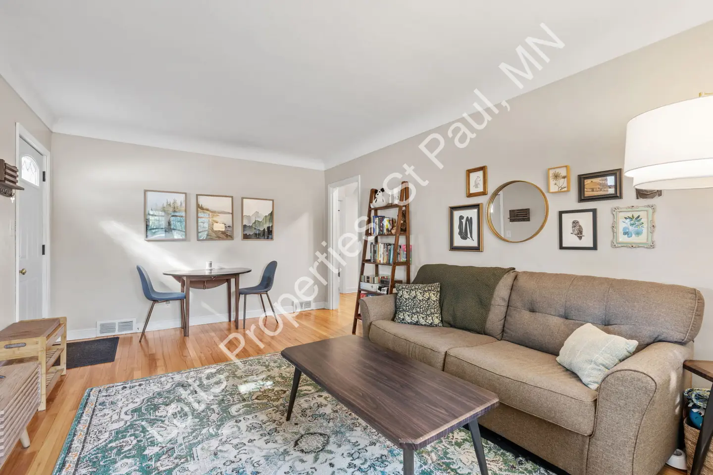 Living room and adjacent dining area with hardwood floors and a decorative gallery wall.