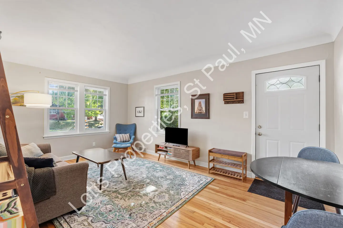 Living room with a glass-paned front door, two windows, and hardwood floors.