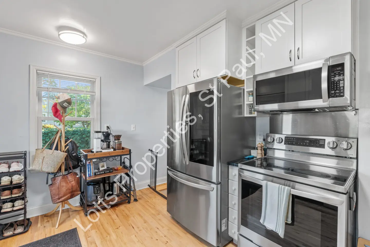 Kitchen showing stainless refrigerator and range with white cabinets and a window nook.