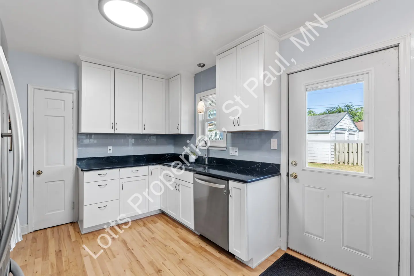 Kitchen corner with white cabinetry, a dishwasher, and a windowed back door.