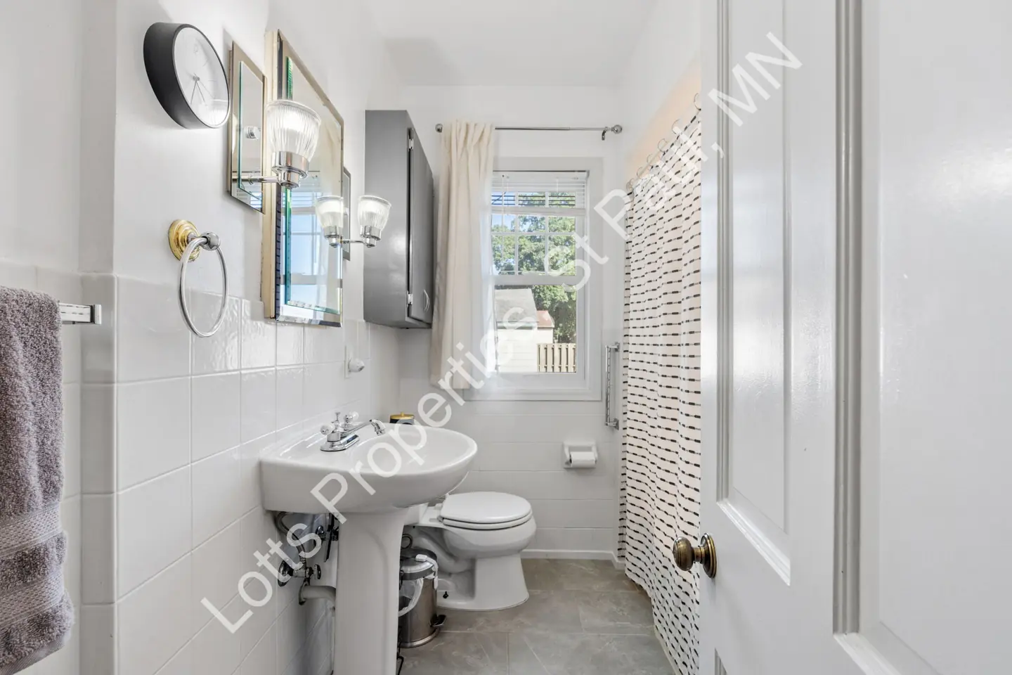 Bathroom at 1444 Alameda with a pedestal sink, toilet, tiled walls, and a window.