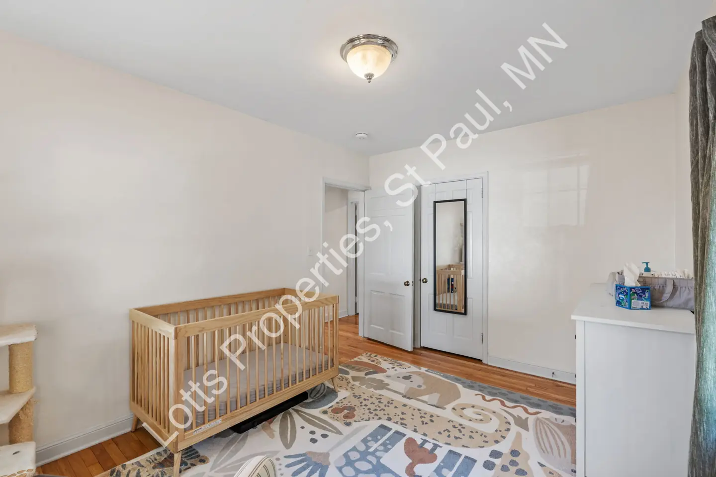 Reverse view of the main-floor bedroom with a crib, closet, and hardwood floors.