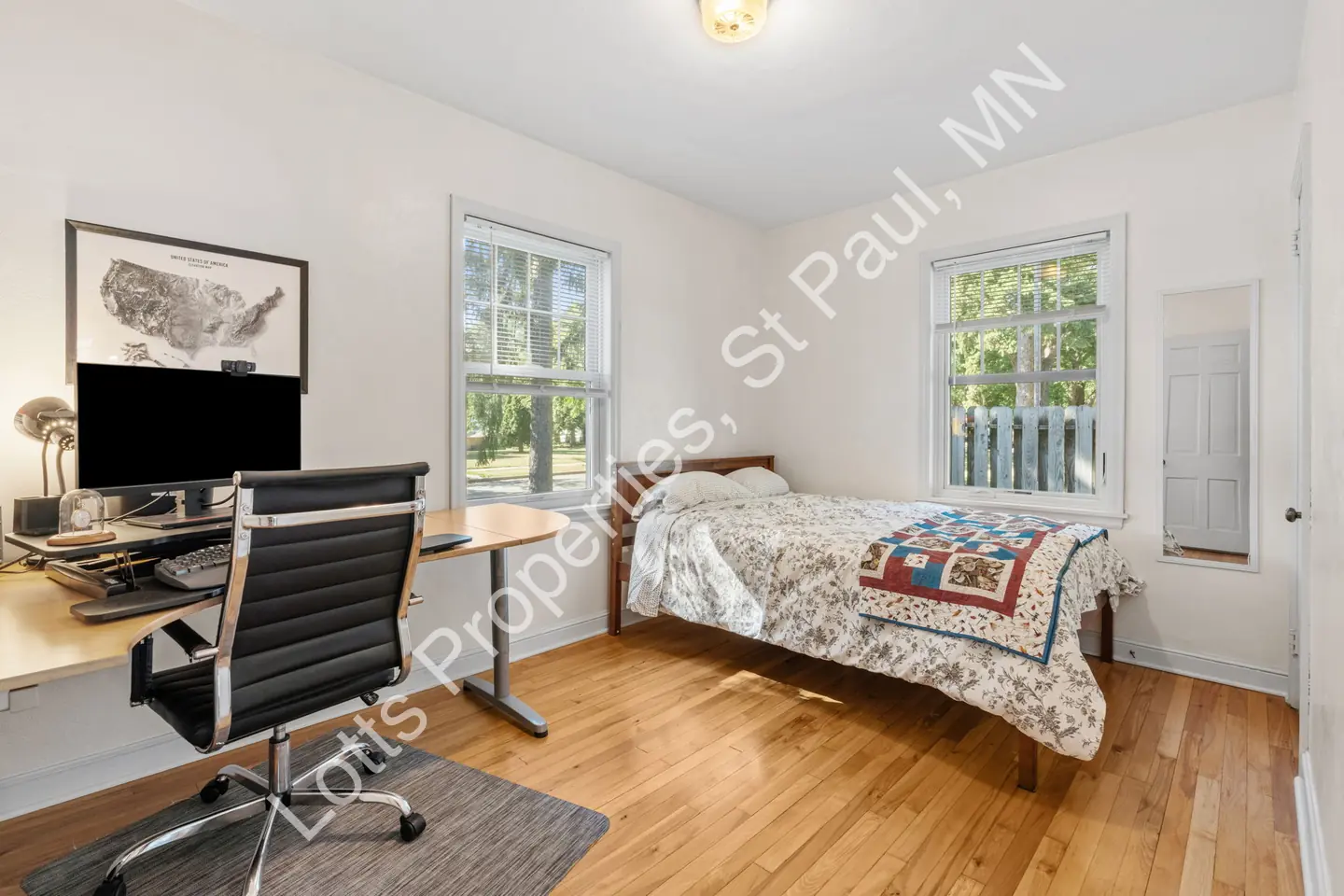 Main-floor bedroom at 1444 Alameda with a bed, desk, and two sunlit windows.
