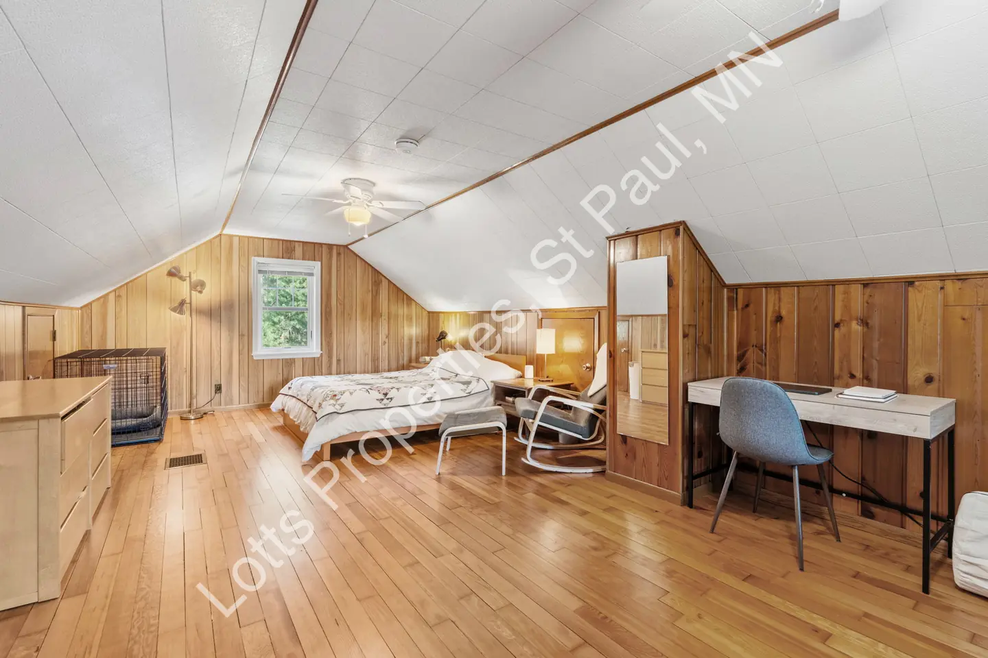 Upstairs wood-paneled bedroom with vaulted ceiling, hardwood floors, and a bed.