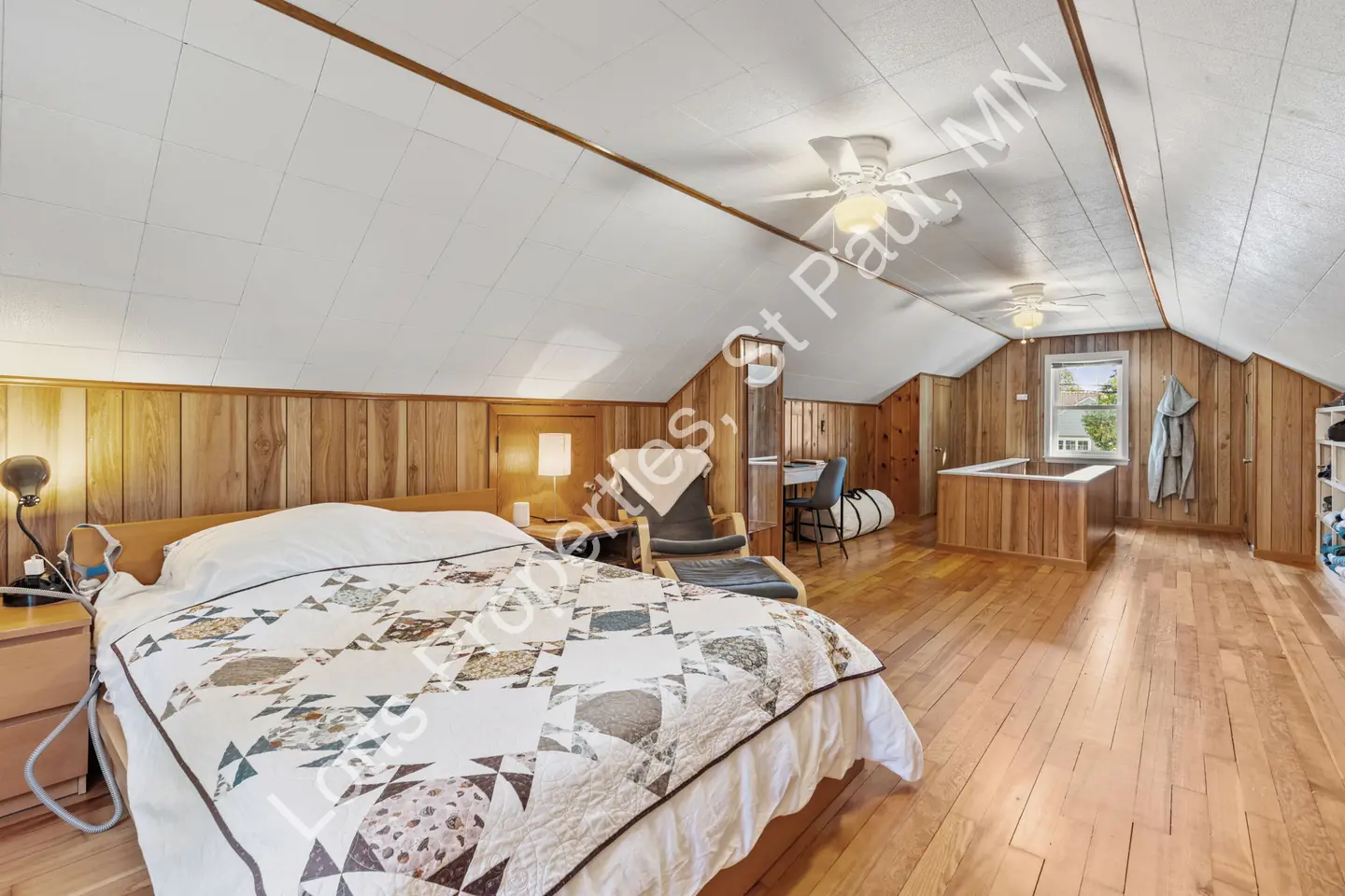 Reverse view of the upstairs paneled bedroom with ceiling fans and built-ins.