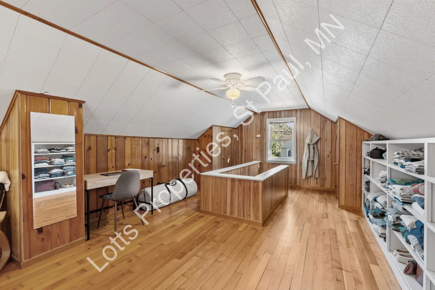 Upstairs bonus area with built-in dresser, desk, and open shelving in wood paneling.