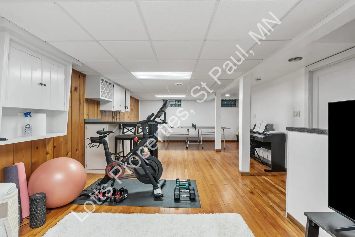 Basement rec room with exercise equipment, ping-pong table, and a bar counter.