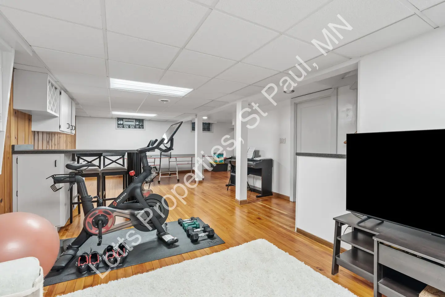 Reverse view of the basement with a fitness area, keyboard, and television.